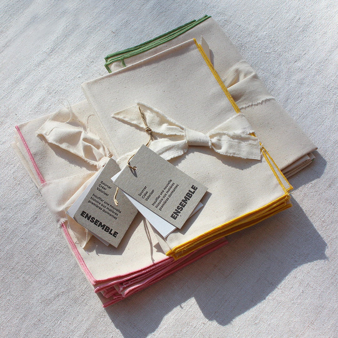 Quatre serviettes en coton écru avec bourdons pastels