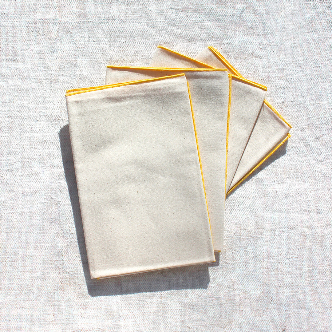 Quatre serviettes en coton écru avec bourdons pastels